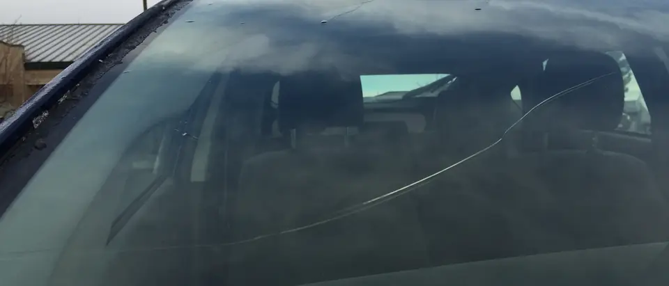 A crack across a windshield spreading from the edge