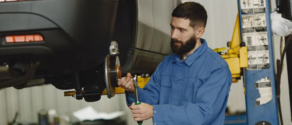 A technician working at a raised wheel in the shop