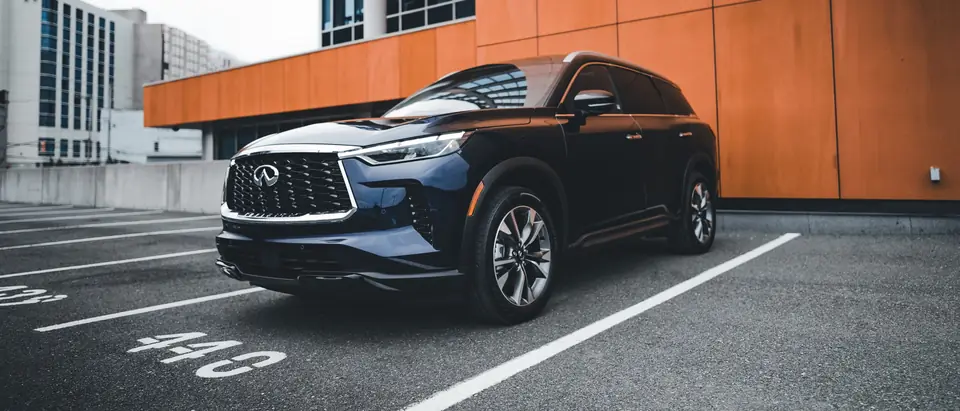 A new dark SUV parked beside a modern building