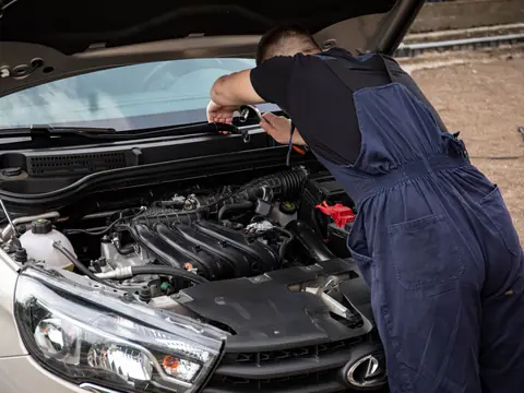 A technician leaning over the front of a silver SUV
