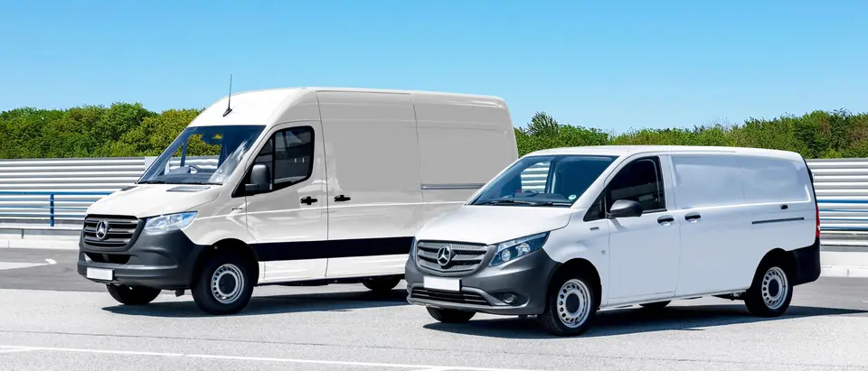 Two white work vans parked in a sunny lot